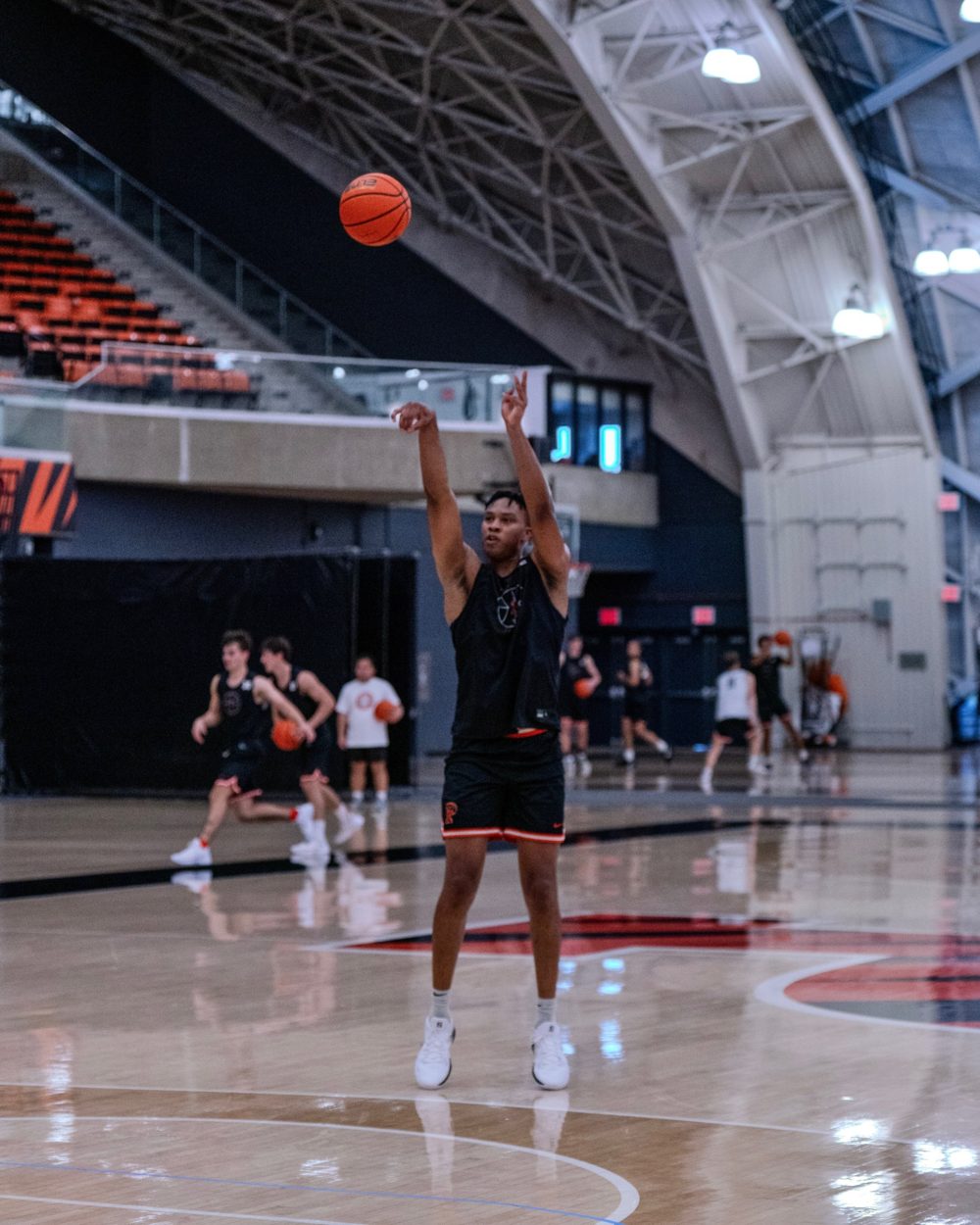 A player follows through on a jumper while teammates work behind him