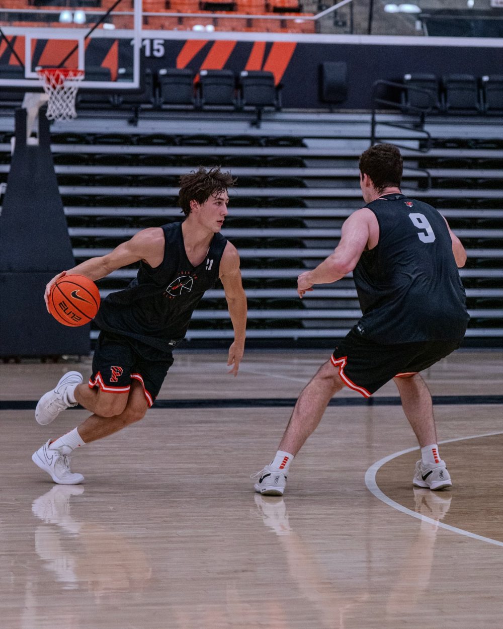 A guard drives past a defender in practice