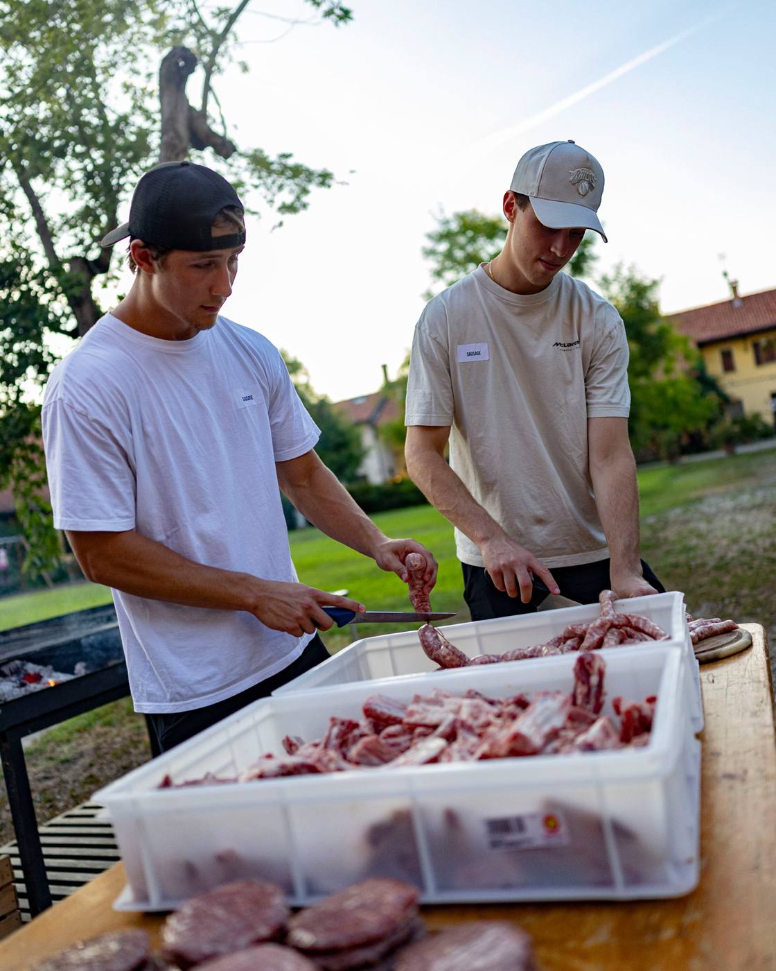 Two players preparing sausages together at the Milan cookout
